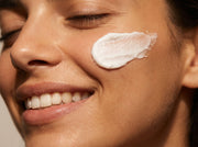 Close-up of a woman's face with a skincare product applied to her cheek.
