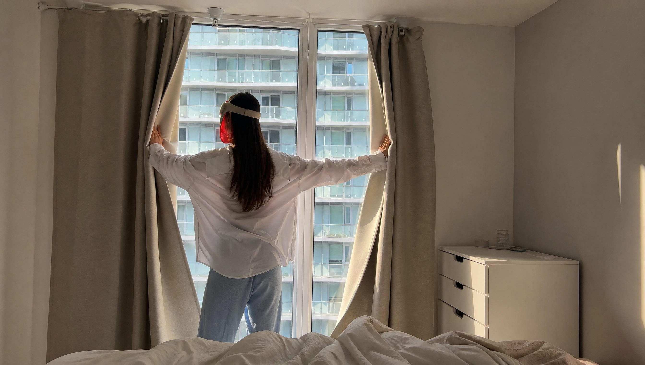 Person opening curtains in a room with a cityscape view