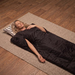 Woman relaxing in a black infrared sauna blanket at home