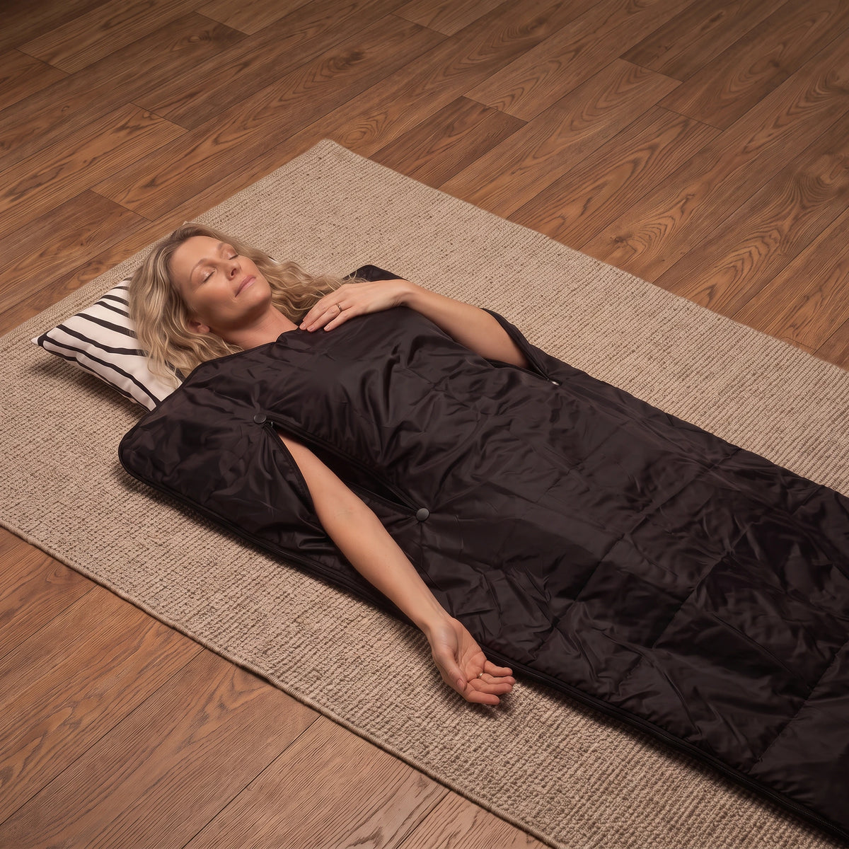 Woman relaxing in a black infrared sauna blanket at home