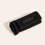 Black Luscent sauna blanket towel insert folded and rolled on an ivory background