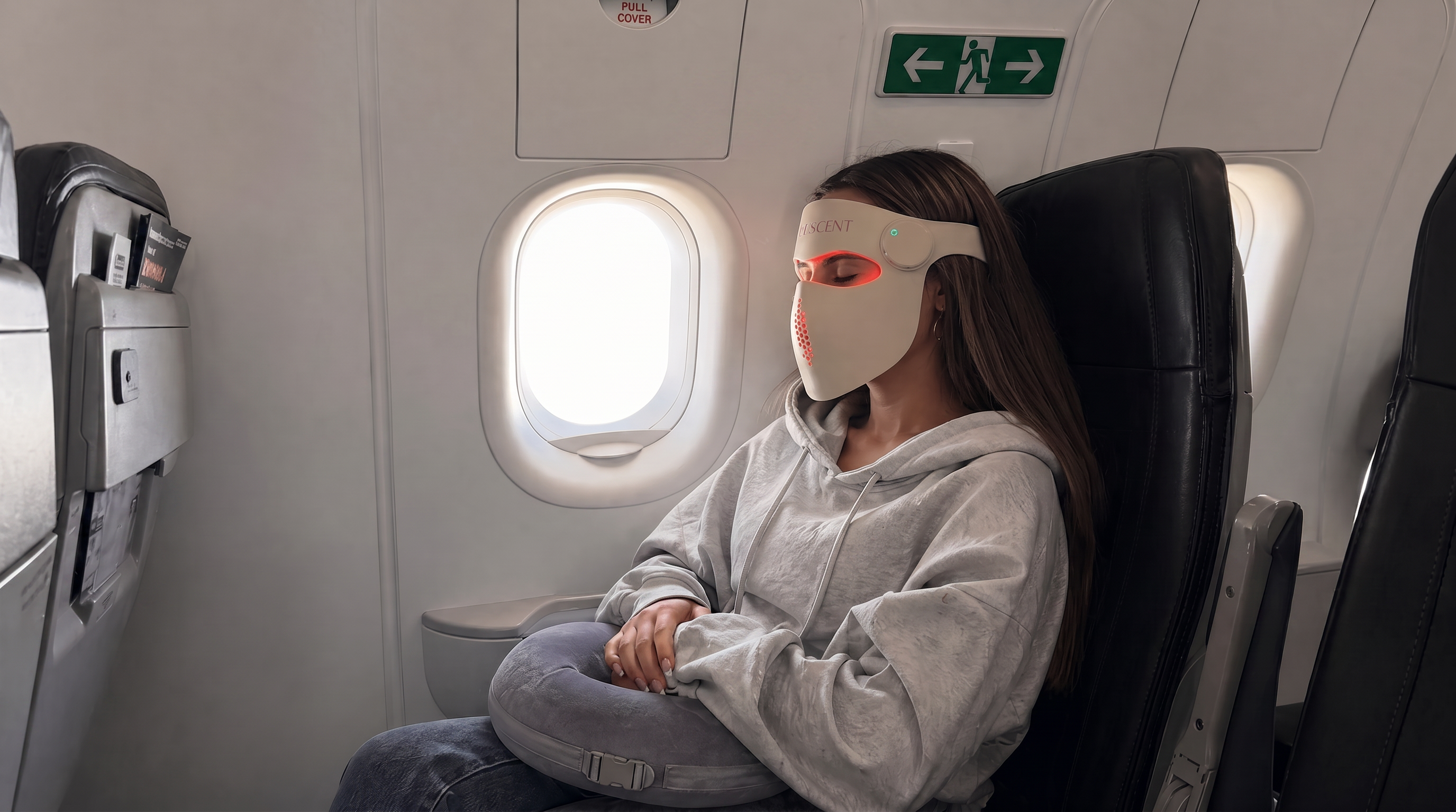 Person sitting in an airplane seat wearing a face mask.