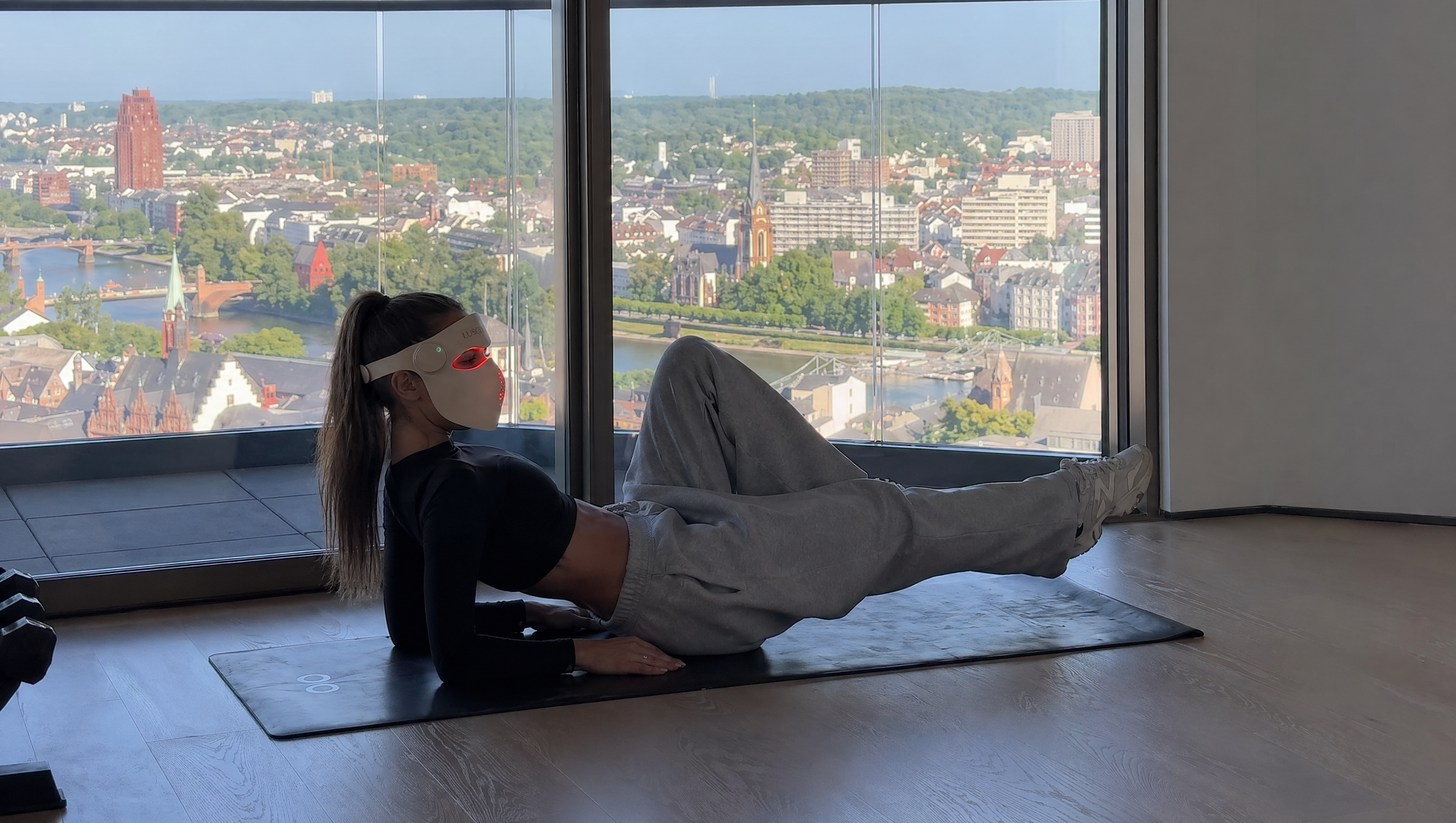 Person exercising on a mat in front of a large window with a cityscape view