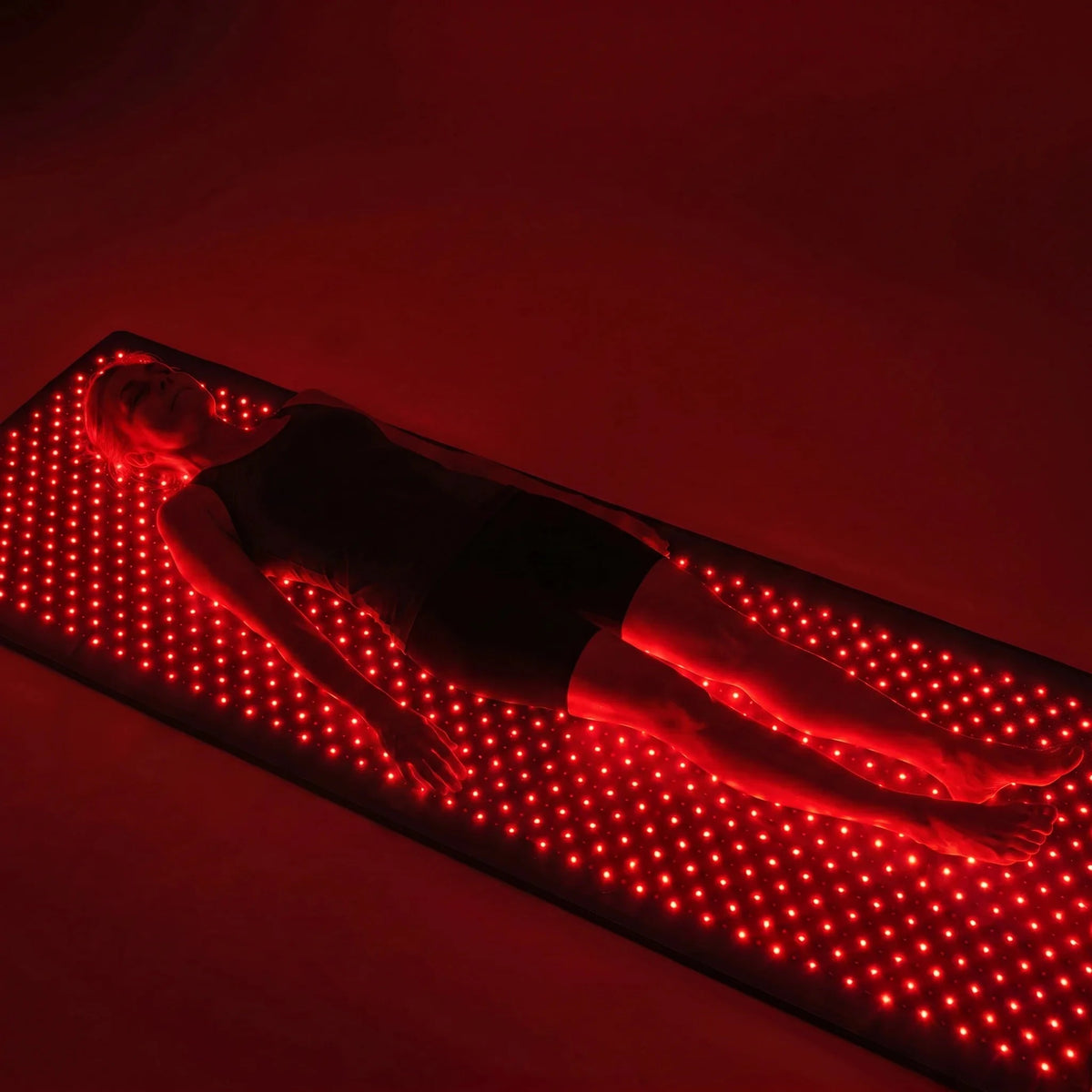 Woman relaxing on the Luscent full-body red light therapy mat